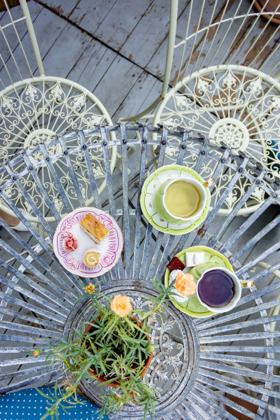 在村里的小屋里喝茶。早餐用的金属桌子和椅子。茶碟上放着棉花糖和茶的瓷杯。图片下载