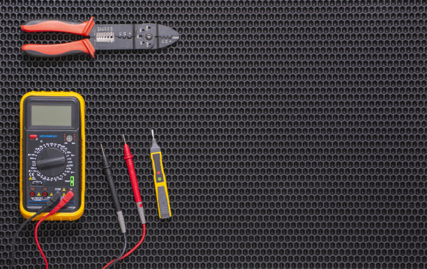 万用表，指示器螺丝刀和剥线器在黑色橡胶垫上图片下载