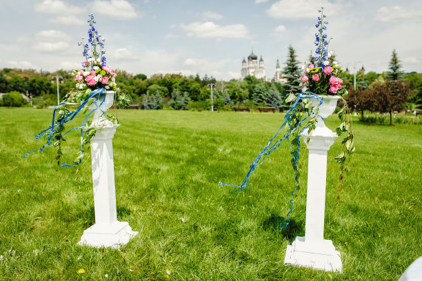 公园里有两根插着彩色花朵的柱子。婚礼的拱门在露天用鲜花和圆柱装饰。婚礼装饰。图片区图片下载