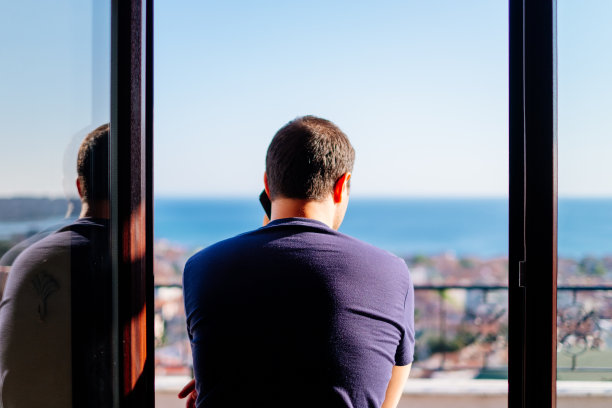 一个单身男人在窗边打电话图片下载