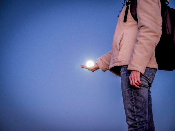 一名女性徒步旅行者双手捧着月亮，这是一种错觉图片下载