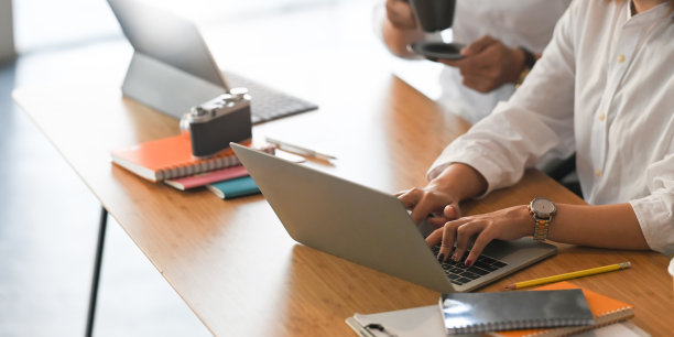 图片的平面设计师团队一起工作的电脑笔记本电脑和平板电脑在木制办公桌周围的办公设备，在舒适的客厅作为背景。图片下载