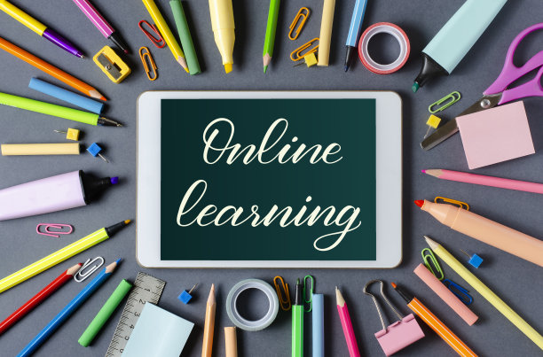 在线学习-在写字板上手写题词。对儿童进行远程训练的概念。黑色背景下的平板电脑和办公用品。图片下载