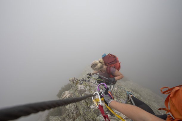 在雾中，一名年轻女子爬上via ferrata图片下载
