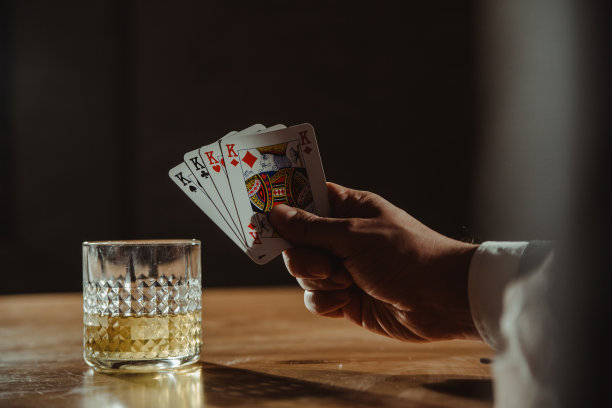 男人打牌和喝威士忌的特写。图片下载