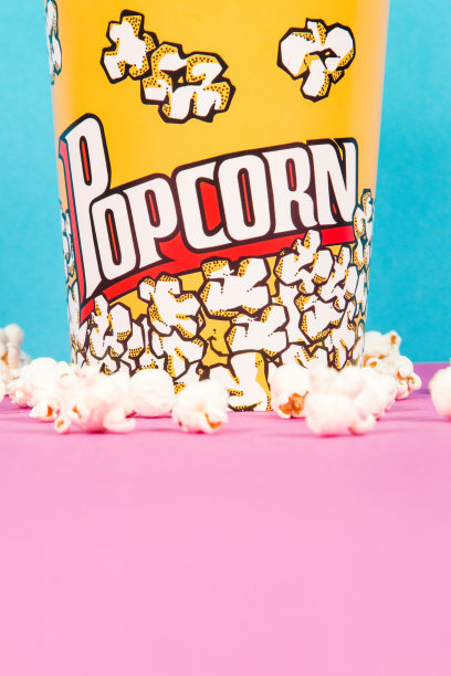 一盒粉红色和蓝色背景的黄色新鲜爆米花图片下载