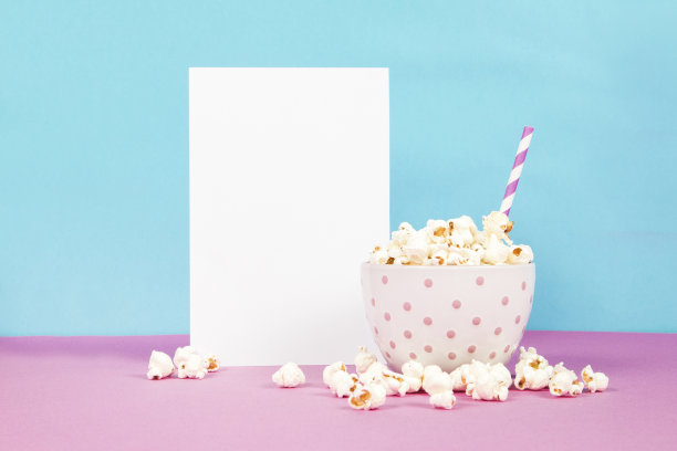 新鲜的爆米花在一个白色的粉红色的碗，粉红色和蓝色的背景与空白纸页图片下载