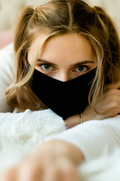 特写美丽的白人妇女与面具。她正在卧室的床上享受。图片下载