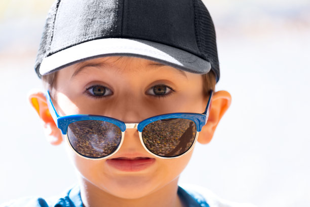 小男孩戴着太阳镜，表现出惊讶的情绪。秋天的公园。快乐的童年概念图片下载