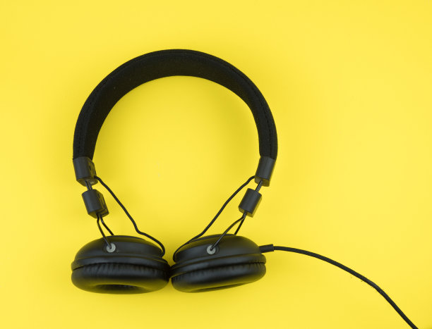 黄色背景上的黑色耳机。娱乐的概念图片下载