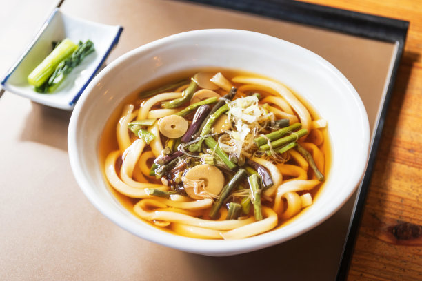 日式乌冬面和汤碗放在桌子上，阳光透过窗户。图片下载