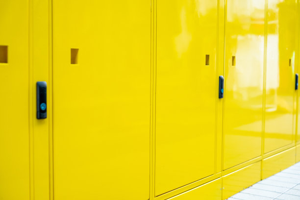 黄色的墙壁和电气控制面板旁边的黄色锁在校学生的储物柜，有号码的储物柜和钥匙给每个学生。装饰和设计。近距离图片下载