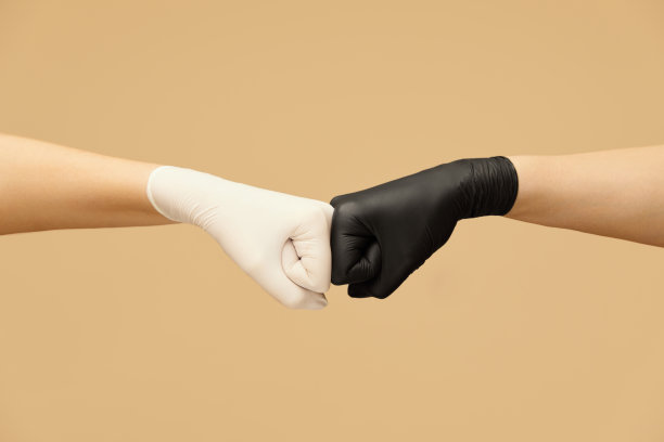 的手势。隔离期间戴着手套碰拳头朋友们在米色背景下问候。预防感染的个人防护。图片下载
