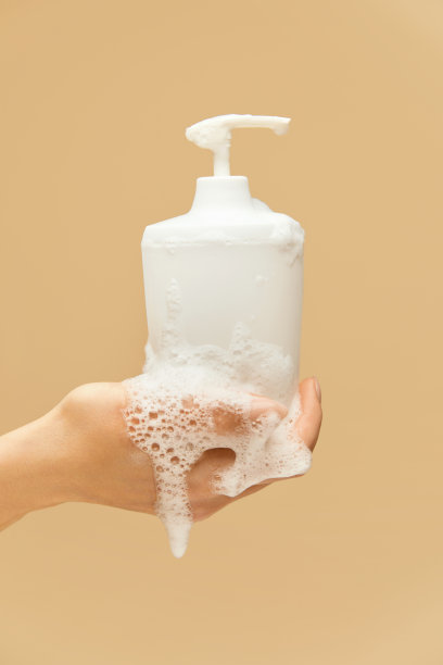 个人卫生。在米色的背景下，用泡沫盖住液体肥皂瓶。洗手预防病毒，保持健康。图片下载