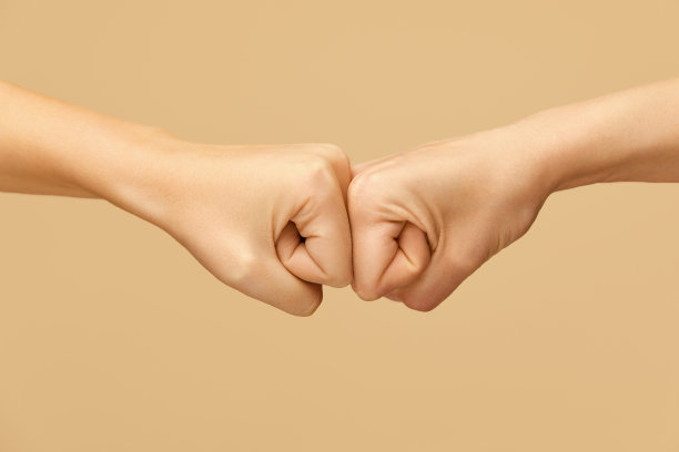 的手势。最好的朋友之间最流行的问候方式。在米色背景下握手。图片下载