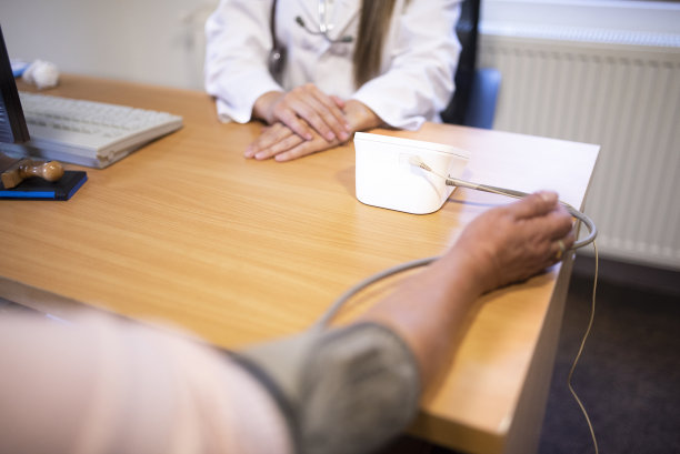 年轻的全科医生测量血压的老年妇女在医院办公室库存照片图片下载