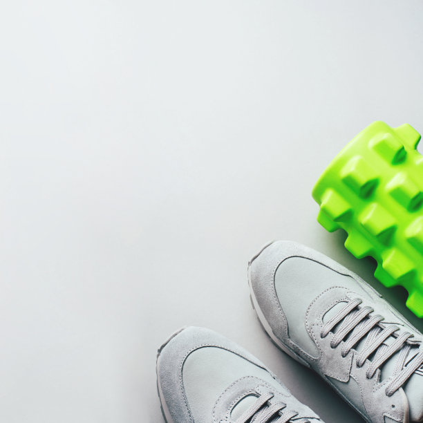 灰色运动鞋和按摩滚筒在灰色背景。图片下载