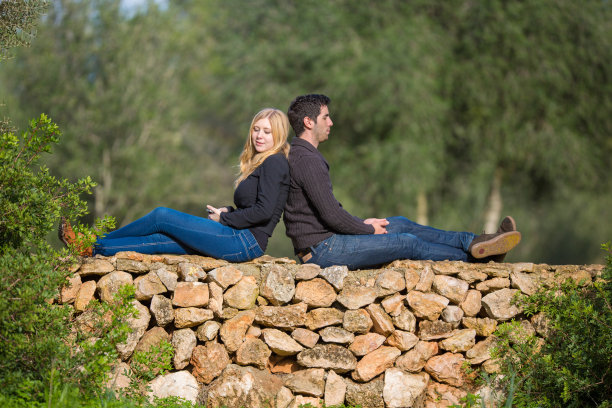 一对夫妇背靠背坐在墙上享受阳光图片下载