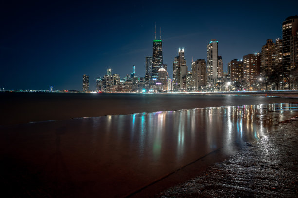 芝加哥城市的天际线夜晚照片与灯光反射的死水冲刷波纹混凝土海岸线在市中心沿密歇根湖。图片下载
