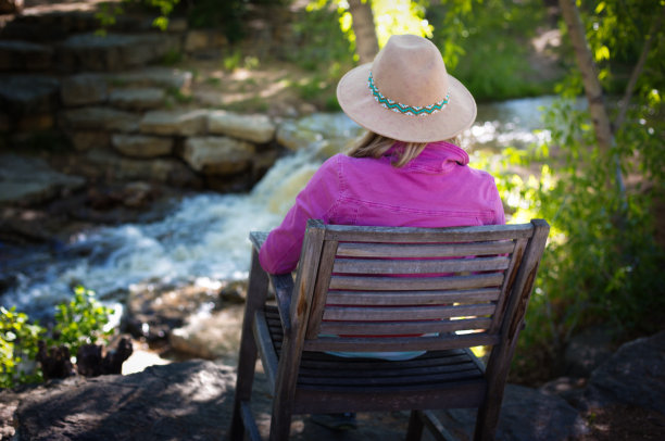 沉思的女人坐在瀑布/溪流附近图片下载