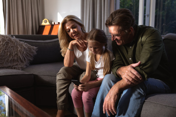 一个白人女孩和她祖父在沙发上玩手机的照片图片下载