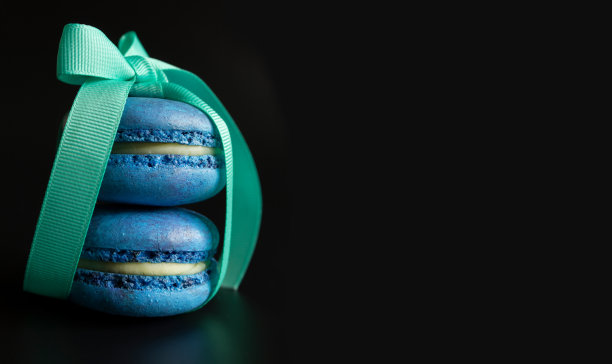 两个蓝色的马卡龙与绿松石缎带在一个深色的背景和文字/复制空间图片下载