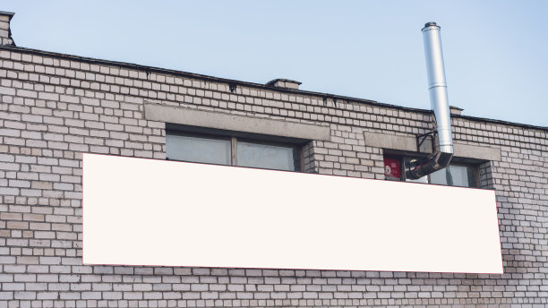 蓝天下，旧厂房的砖墙上挂着巨大的空白横幅图片下载