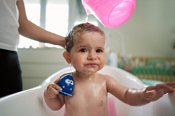 困惑的女婴正在被她的母亲洗图片下载