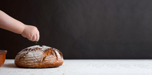 孩子的手把面包放在面包店的桌子上。背景黑色墙体混凝土图片下载