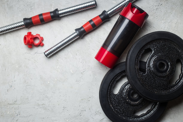 铁哑铃和乳清蛋白摇摇杯，健身或健美概念背景，灰色水泥地面上的产品照片图片下载