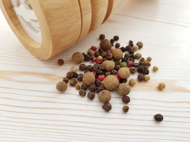 散落的黑胡椒，香料和香料磨在一个轻的背景与木制纹理。原料烹饪。图片下载