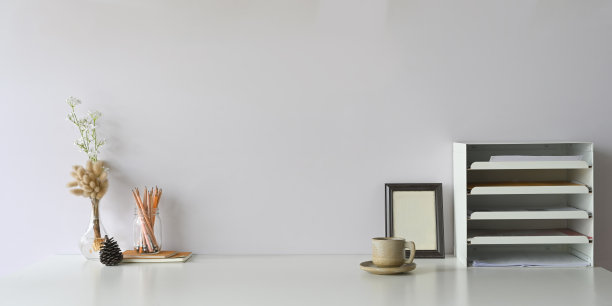 文件架、相框、玻璃花瓶里的铅笔、松果、笔记本和瓶子里的野草环绕的工作空间咖啡杯。图片下载