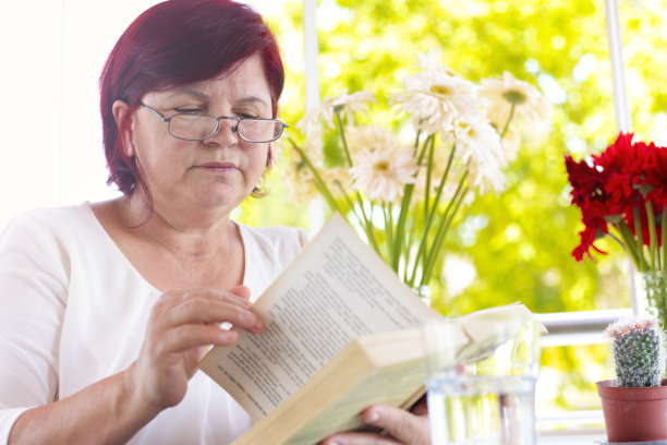 快乐冷静成熟的女人在她房子的阳台上看书。爱好和活动概念。图片下载