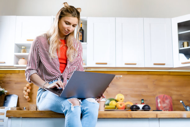 室内成年妇女的肖像。概念与复制空间。女孩很开心，微笑着。温暖的家的氛围。她正在用手提电脑工作图片下载