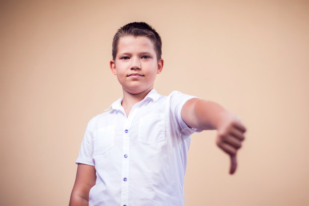 一个小男孩的肖像，拇指朝下。童年与情感概念图片下载
