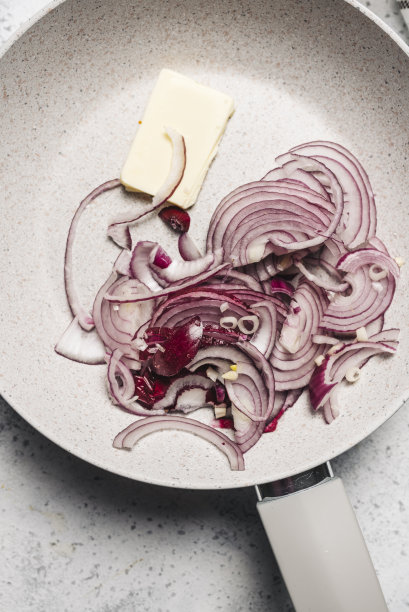 用平底锅把红洋葱和黄油放在厨房的火上图片下载