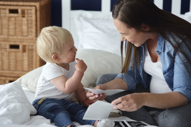 好奇的蹒跚学步的孩子在看他未来的弟弟或妹妹的照片图片下载