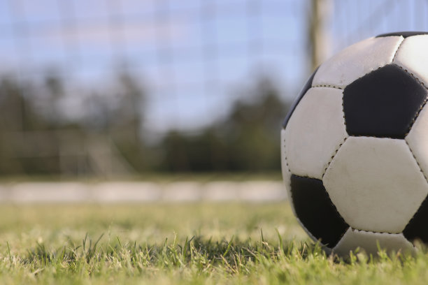 在学校校园的体育场球场的球门网中的足球。图片下载