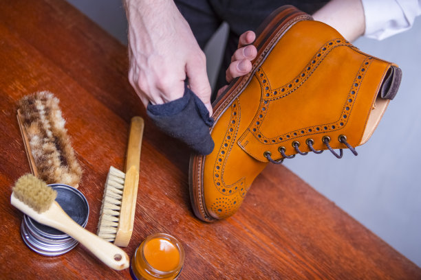 工人的手的特写与清洁布用于抛光棕色高德比靴。在工作室对抗格雷。水平方向图片下载