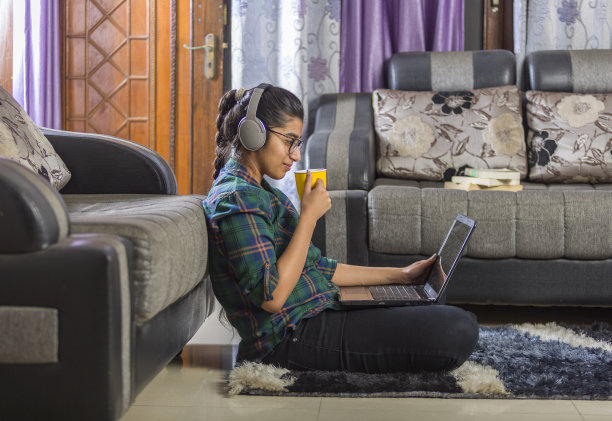 女孩在家里用笔记本电脑和耳机看媒体内容图片下载