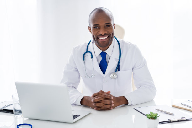 家庭医生的照片黑皮肤的加油家伙牙齿的微笑顾问笔记本桌子处方，帮助病人控制恐慌恐惧的风险流行病穿白色的实验室大褂办公室诊所室内图片下载