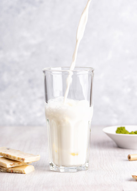 往玻璃杯里倒牛奶。白巧克力和抹茶图片下载