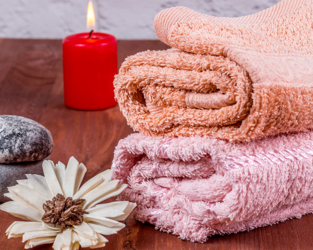 毛巾，一朵花和一堆石头，背景是一支蜡烛图片下载