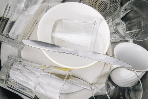 在水槽里洗过盘子，干净光亮。各种各样的玻璃杯、餐具和盘子。图片下载