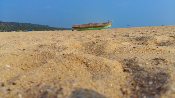 印度喀拉拉邦特里凡得鲁姆的沙阿齐马拉海滩的景观图片，一艘未聚焦的渔船停在沙滩上。图片下载