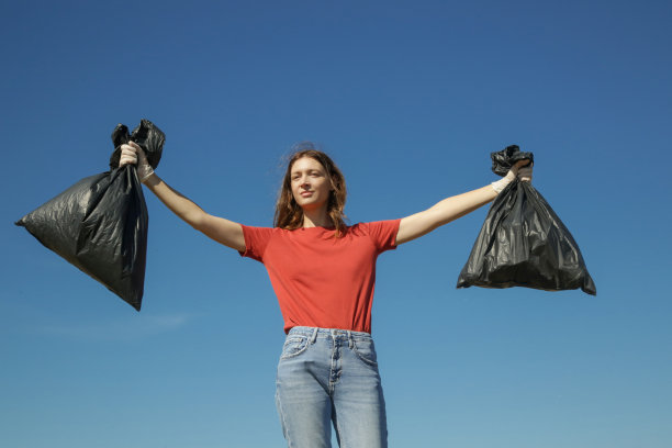 环保人士收集塑料垃圾的照片。志愿者拿着装满垃圾的塑料袋图片下载
