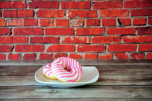 盘子上有两个新鲜的粉色甜甜圈。特写镜头。图片下载