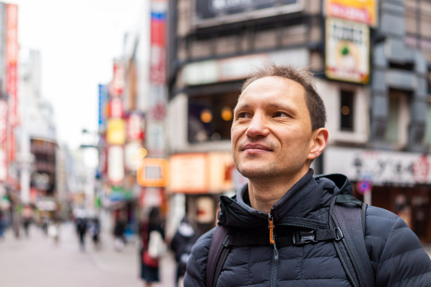 东京，日本涉谷区与快乐的人游客在市中心著名的Koen dori购物街的特写，以丰富多彩的建筑为背景的散景图片下载