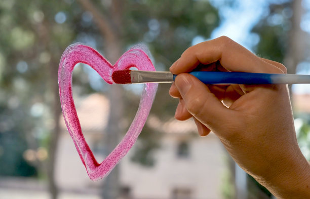年轻女子在家里的窗户上画心图片下载