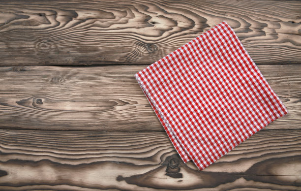 红色格子厨房布在深色木质背景上，野餐毛巾折叠在桌面上视图。图片下载